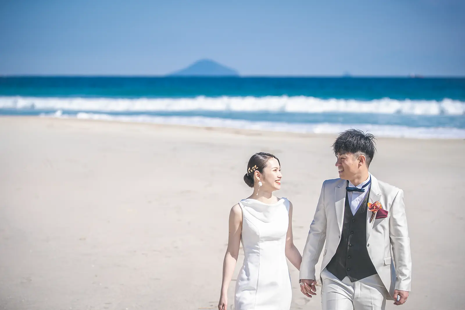 伊豆・白浜の輝く白い砂浜と、透明度の高い青い海を背景に撮影されたフォトウェディング。ウェディングドレスとタキシードが海に映える、開放感あふれるロケーションフォト。