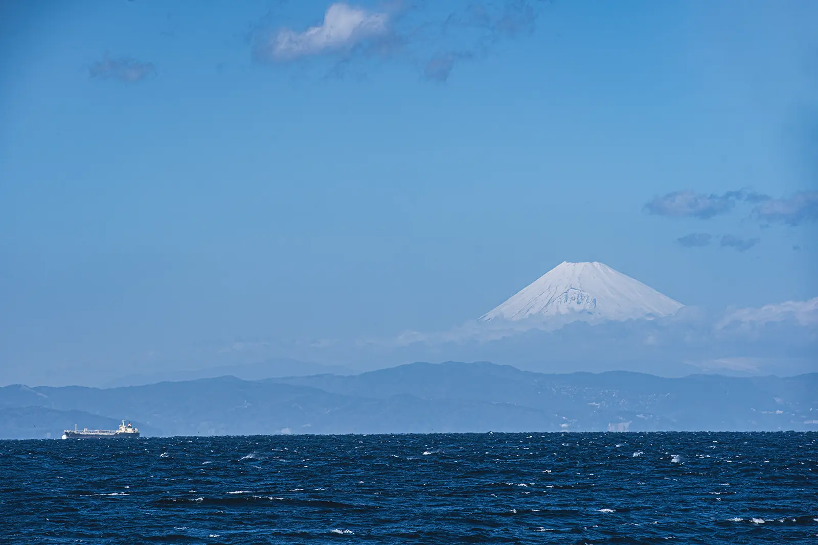 伊豆大島の海越しに見える富士山と青空の風景写真