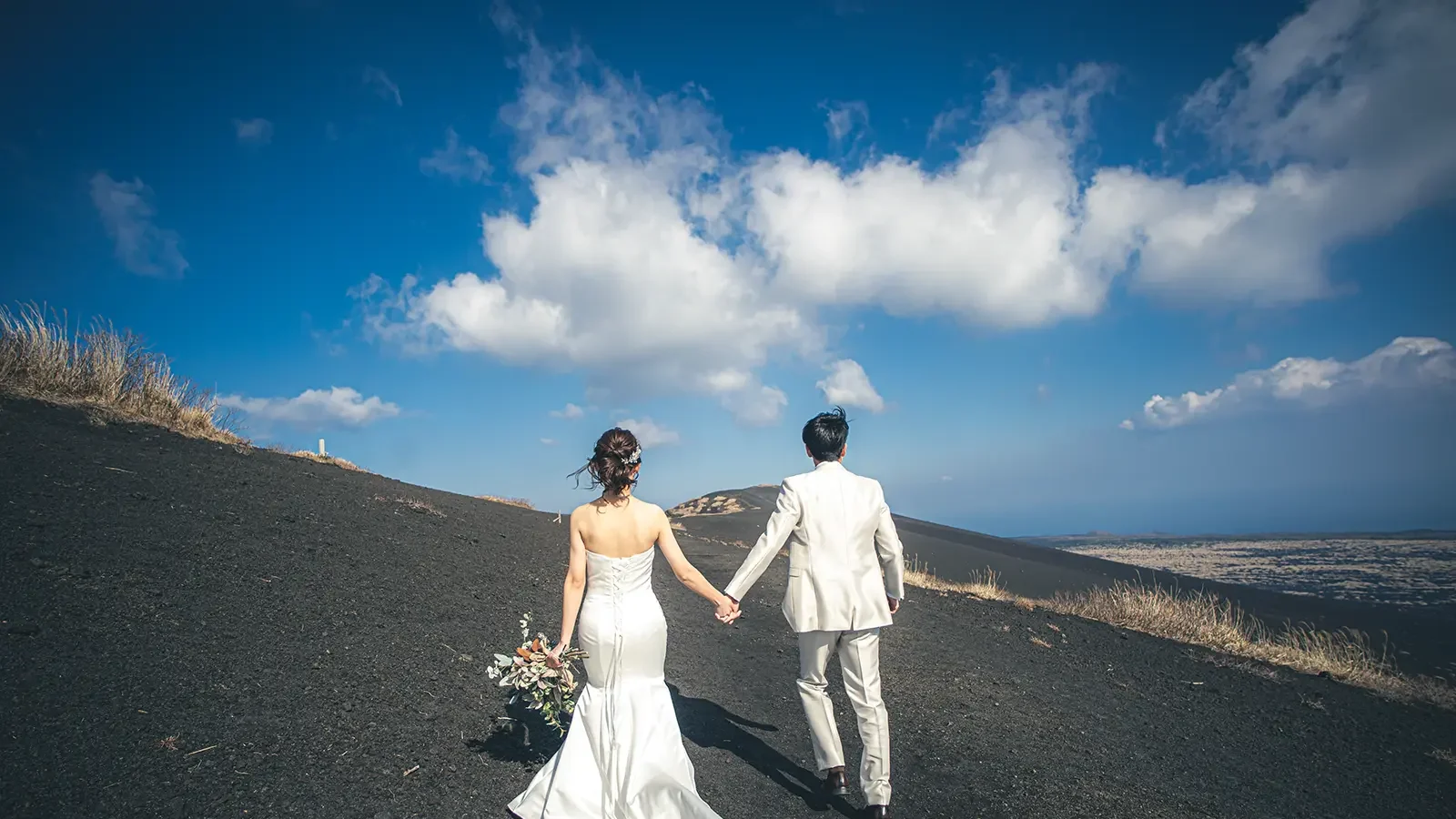伊豆大島の裏砂漠を手をつないで歩く新郎新婦のフォトウェディング写真