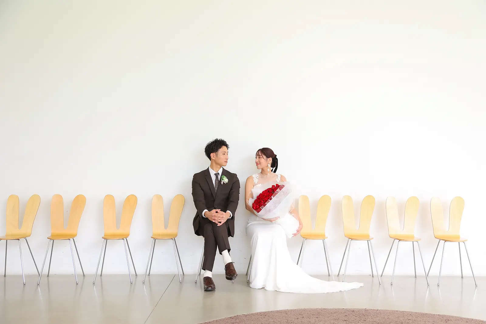 金沢21世紀美術館の白い空間と椅子を背景に座る新郎新婦