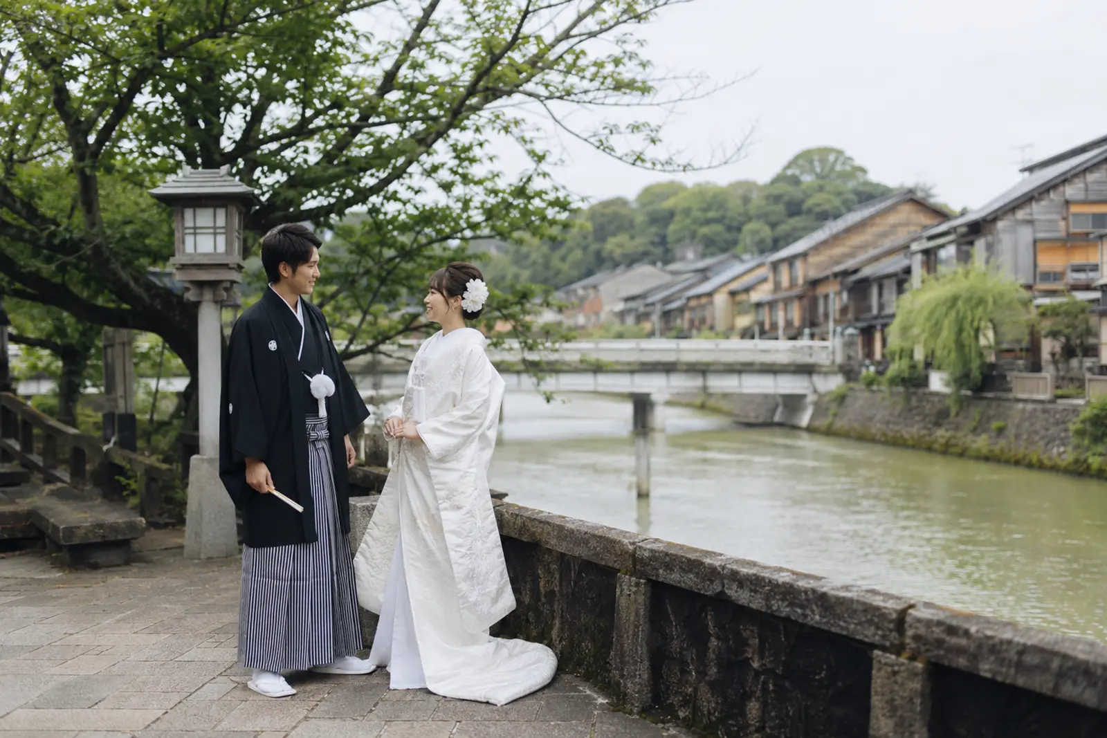 金沢の浅野川周辺で白無垢の新婦と紋付袴の新郎が向かい合う和装フォトウェディング写真