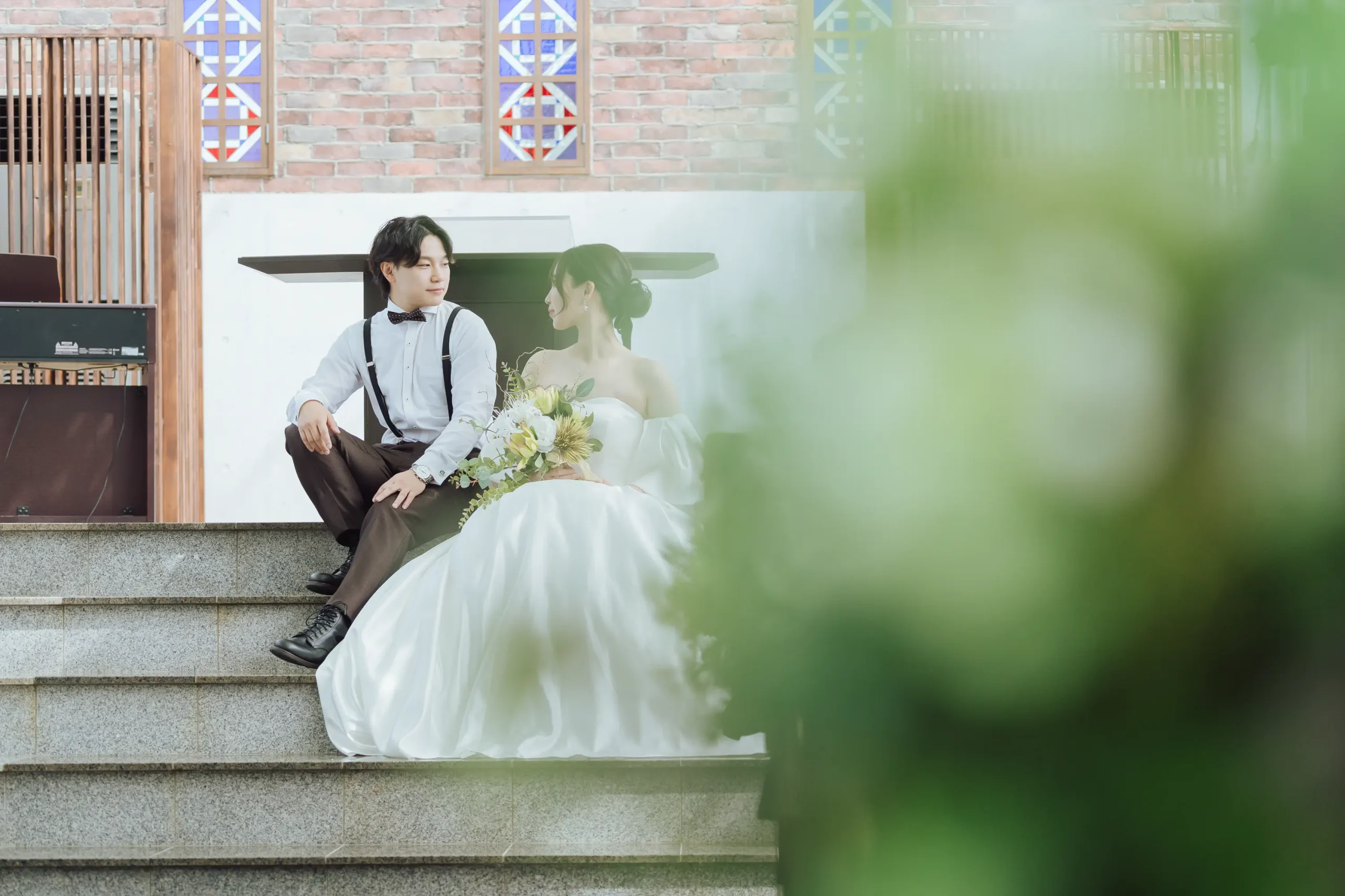 金沢・ぶどうの森のチャペルの階段に腰かけブーケを持つ新婦と隣に座る新郎