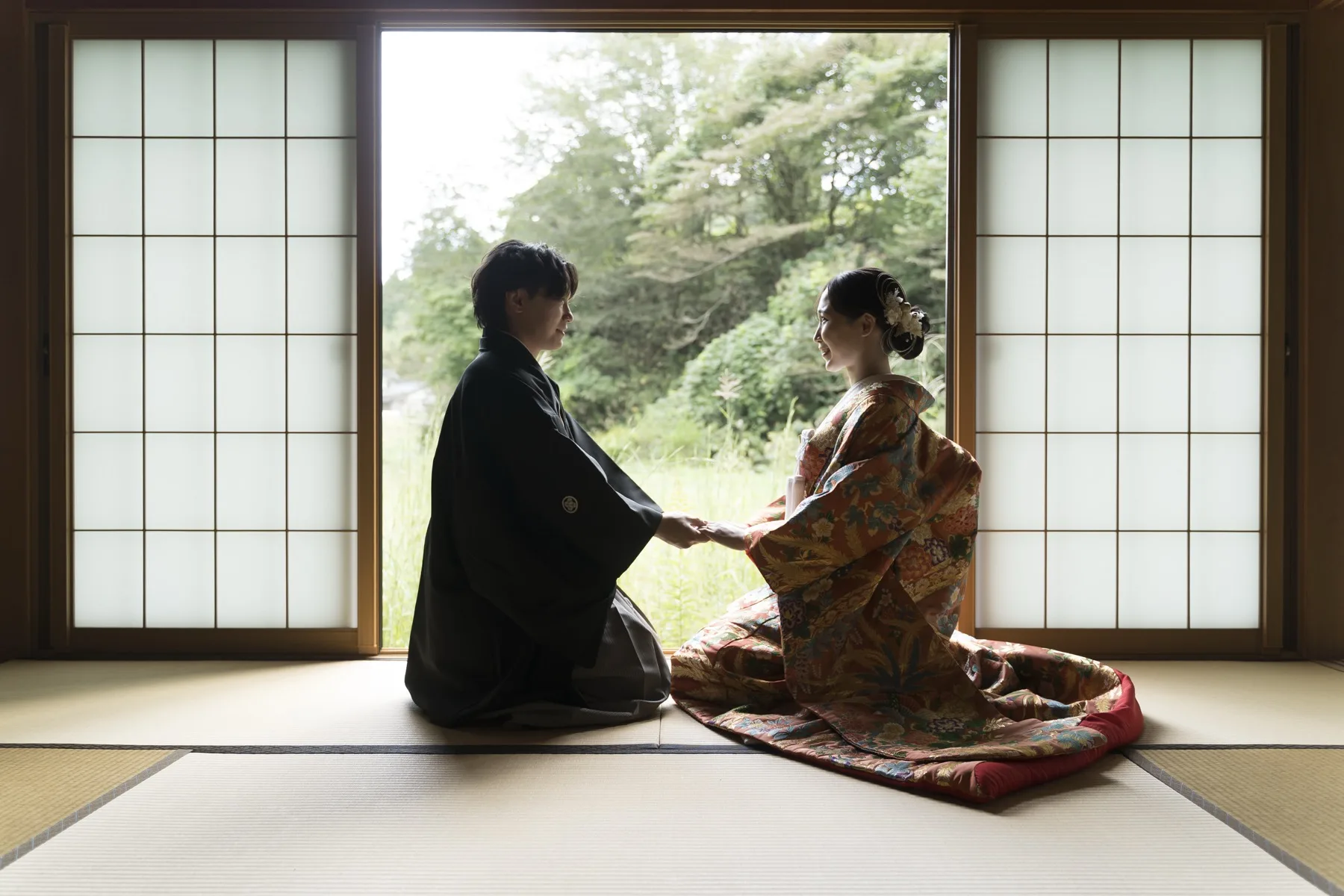 和室で向かい合い手を取り合う色打掛の新婦と黒紋付の新郎、金沢の和装フォトウェディング
