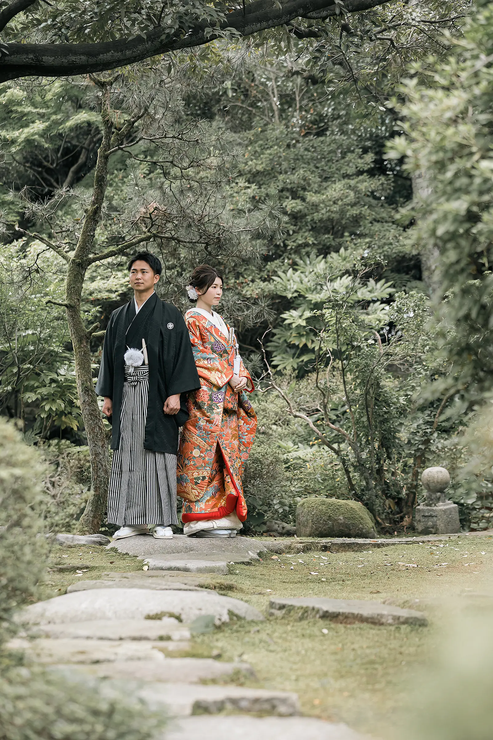 松任ふるさと館の日本庭園で赤い色打掛の花嫁と紋付袴の新郎が立つ和装前撮り