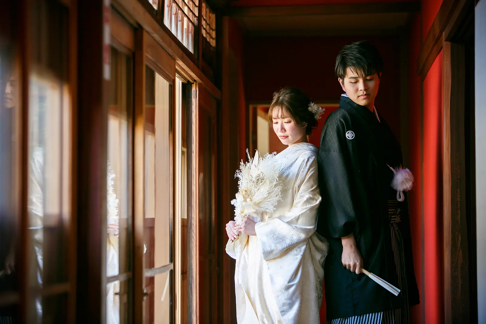 松任ふるさと館の廊下で白無垢の花嫁と紋付袴の新郎が背中合わせに立つ和装前撮り