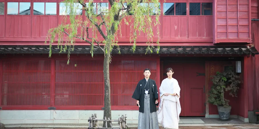 ひがし茶屋街の赤い建物を背景に撮影する和装フォトウェディング
