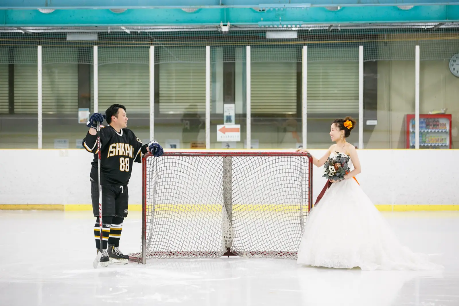 アイスホッケーゴールを挟んで向かい合う新郎新婦の金沢フォトウェディング