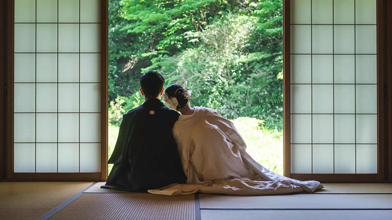 和室スタジオの窓辺で寄り添う新郎新婦の和装前撮り写真