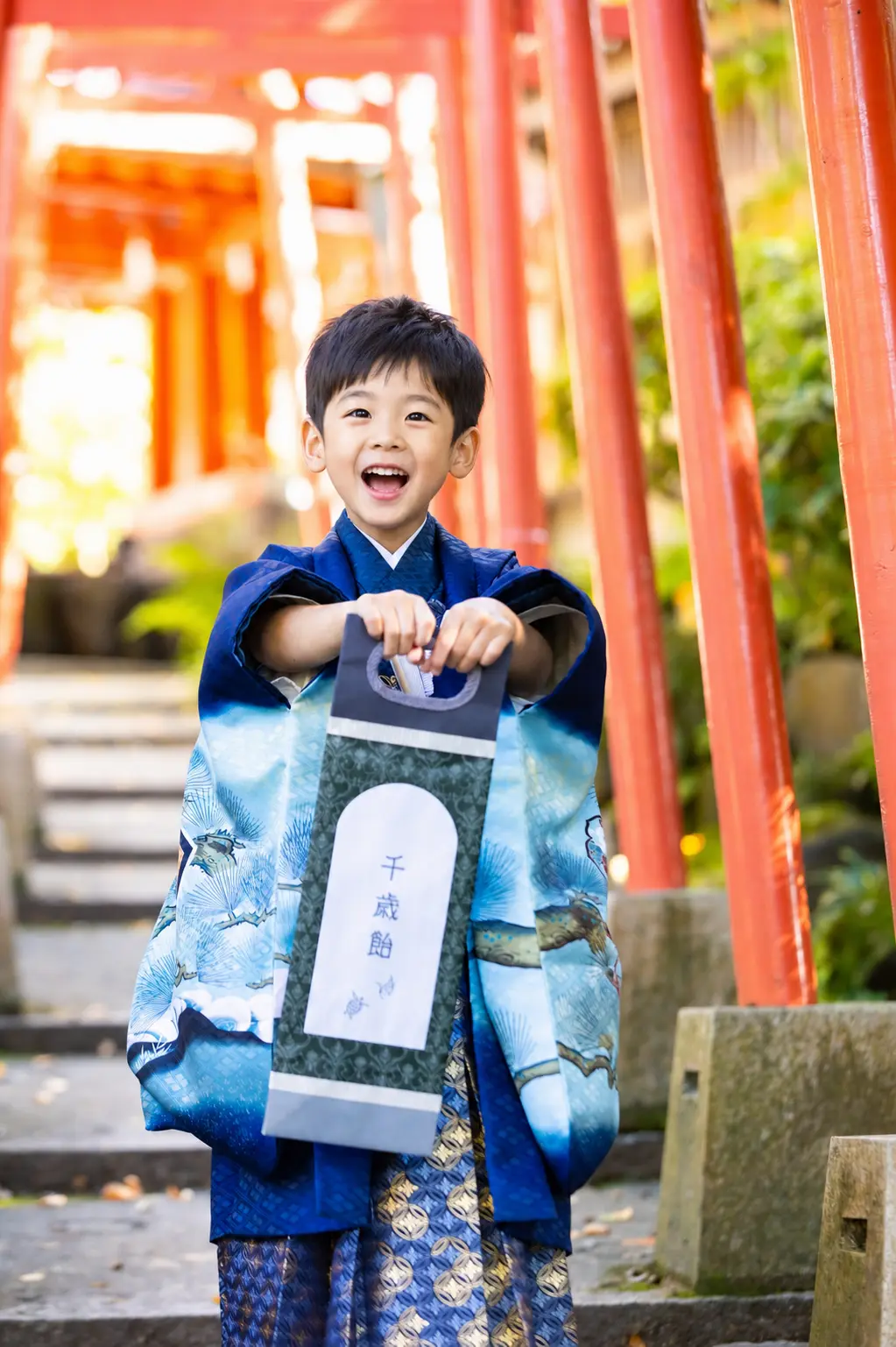 「千歳飴」と書かれた紙袋を両手で提げる羽織袴の5歳の男の子、七五三（金澤神社・金沢）