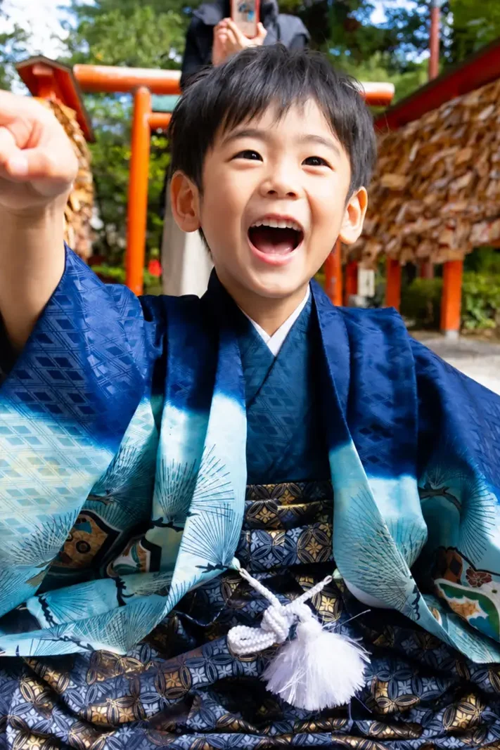 朱の鳥居と絵馬が掛かる棚を背に大きく笑う羽織袴の5歳の男の子、七五三（金澤神社・金沢）