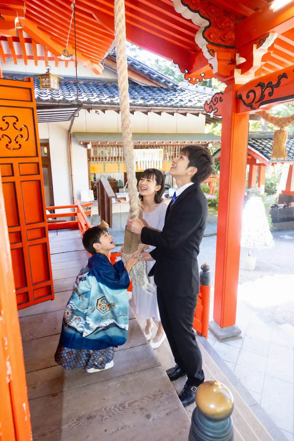 金澤神社の拝殿で本坪鈴の綱を家族3人で握って見上げる七五三の5歳の男の子（金沢）