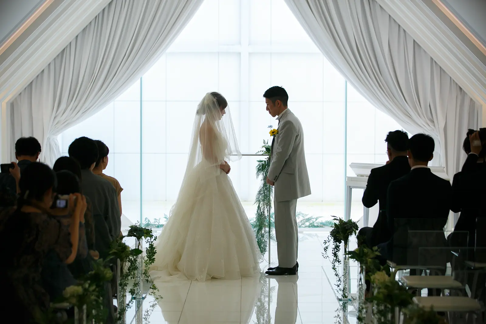 金沢国際ホテルのチャペルで家族に見守られながら挙式風に撮影する新郎新婦の写真