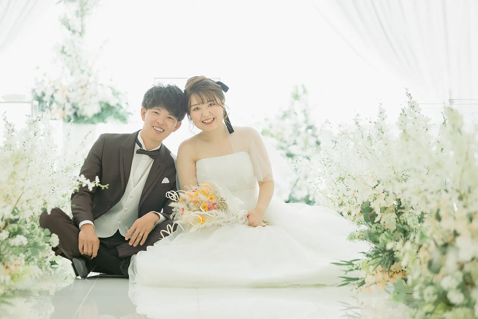 金沢国際ホテルのチャペルで花に囲まれて座る新郎新婦のフォトウェディング写真