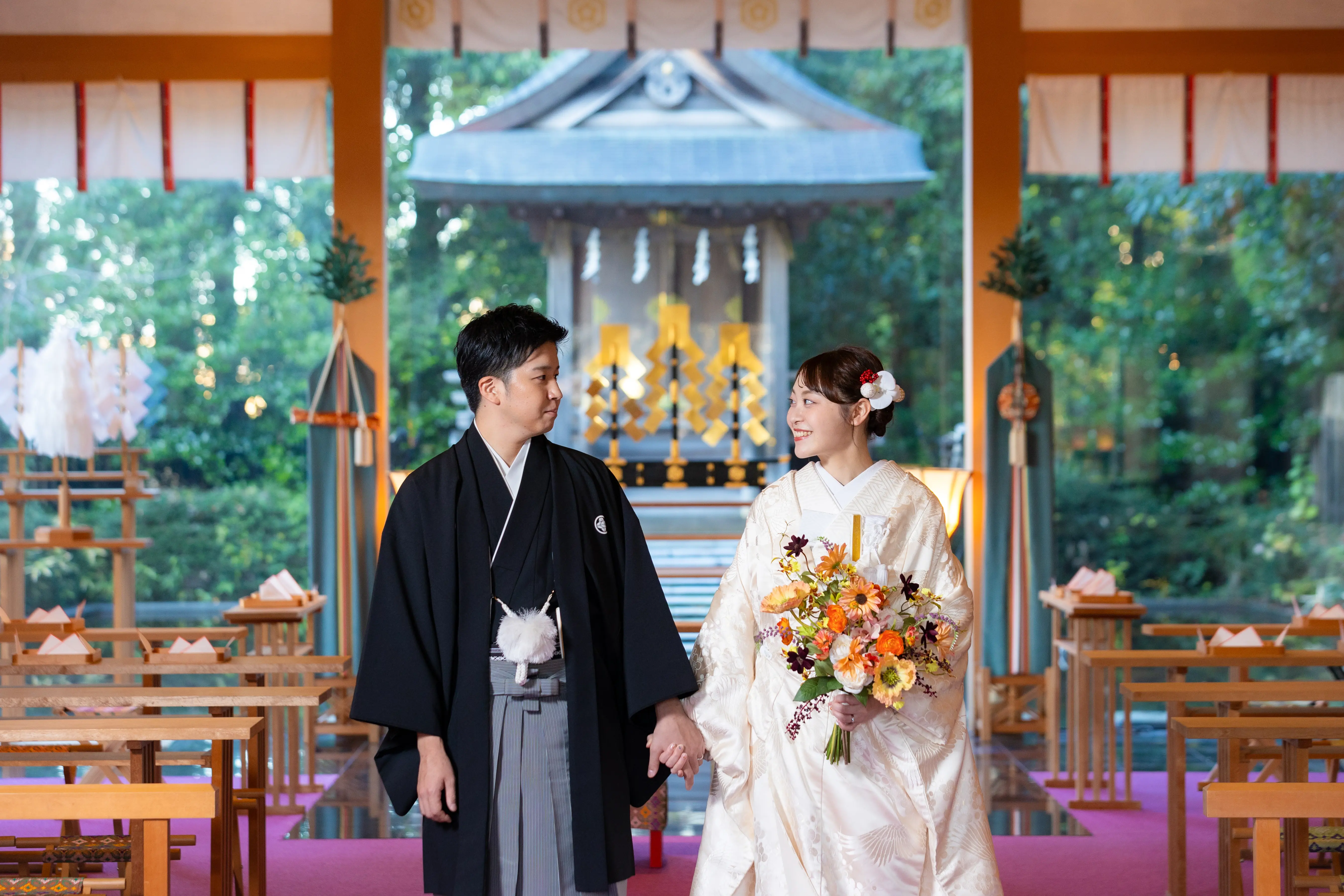 金沢国際ホテルの神殿で夕方の光の中に見つめ合う白無垢と秋色ブーケの新婦、紋付袴の新郎