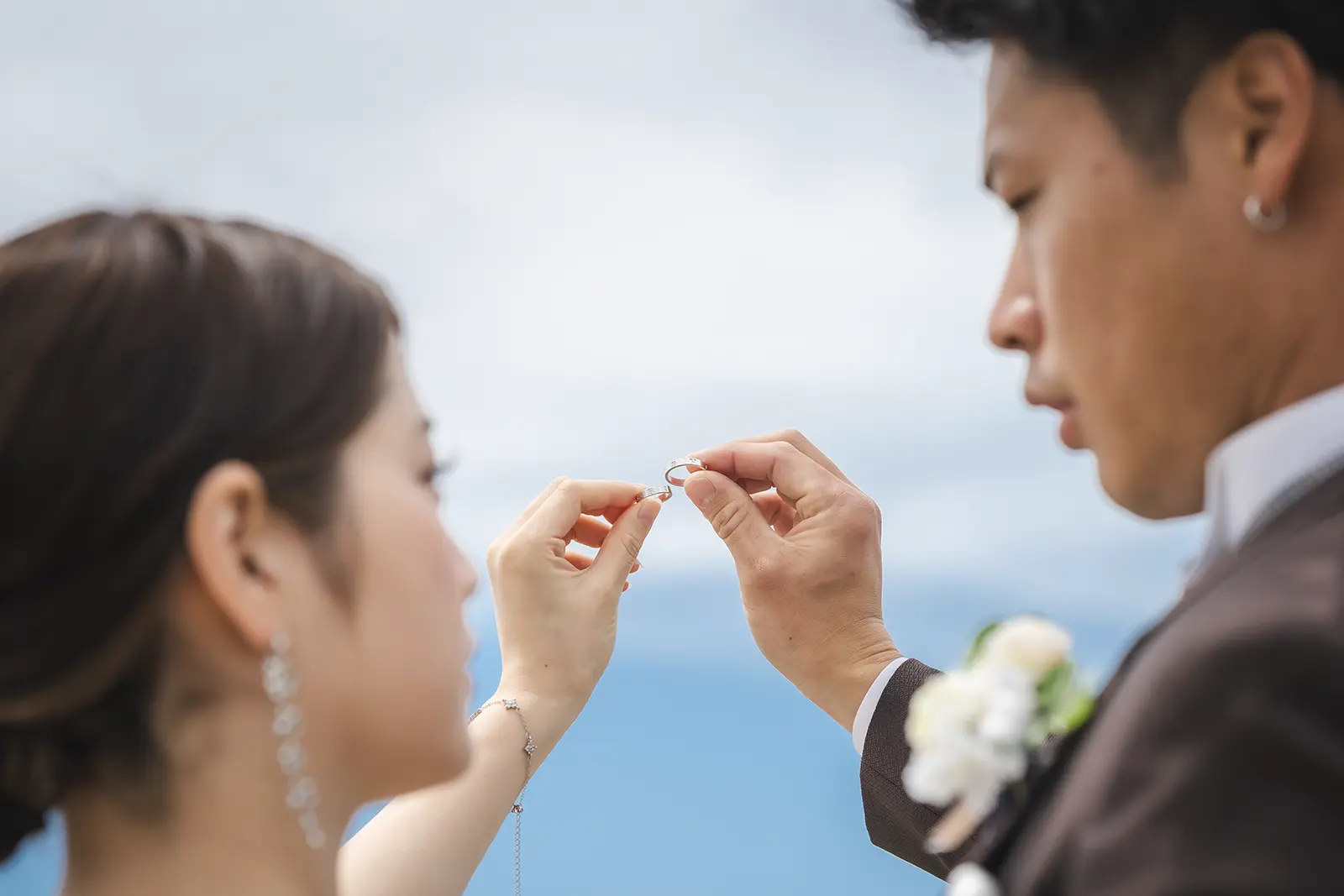 海辺で指輪を見せ合う新郎新婦の手元