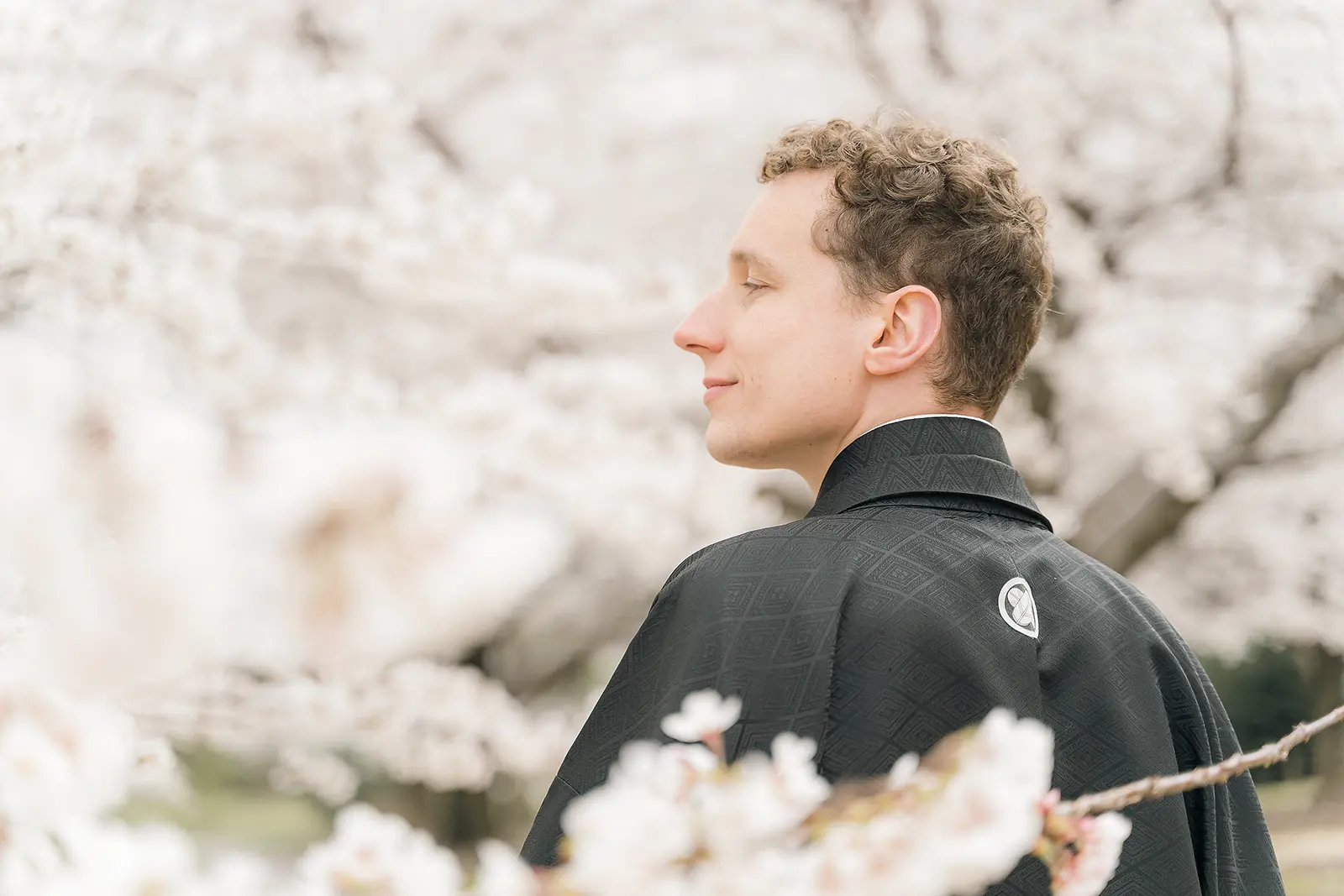 桜を背景に黒紋付姿の新郎を写した前撮り写真