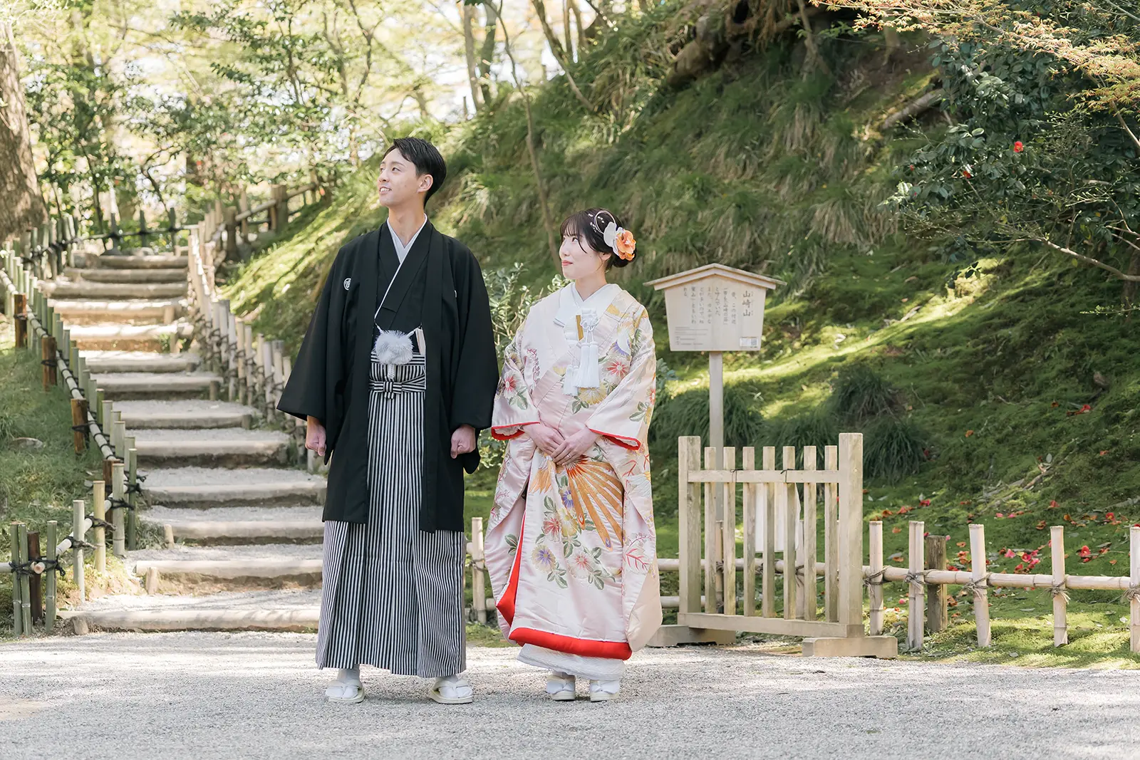 金沢の庭園で手をつないで立つ和装姿の新郎新婦の前撮り写真