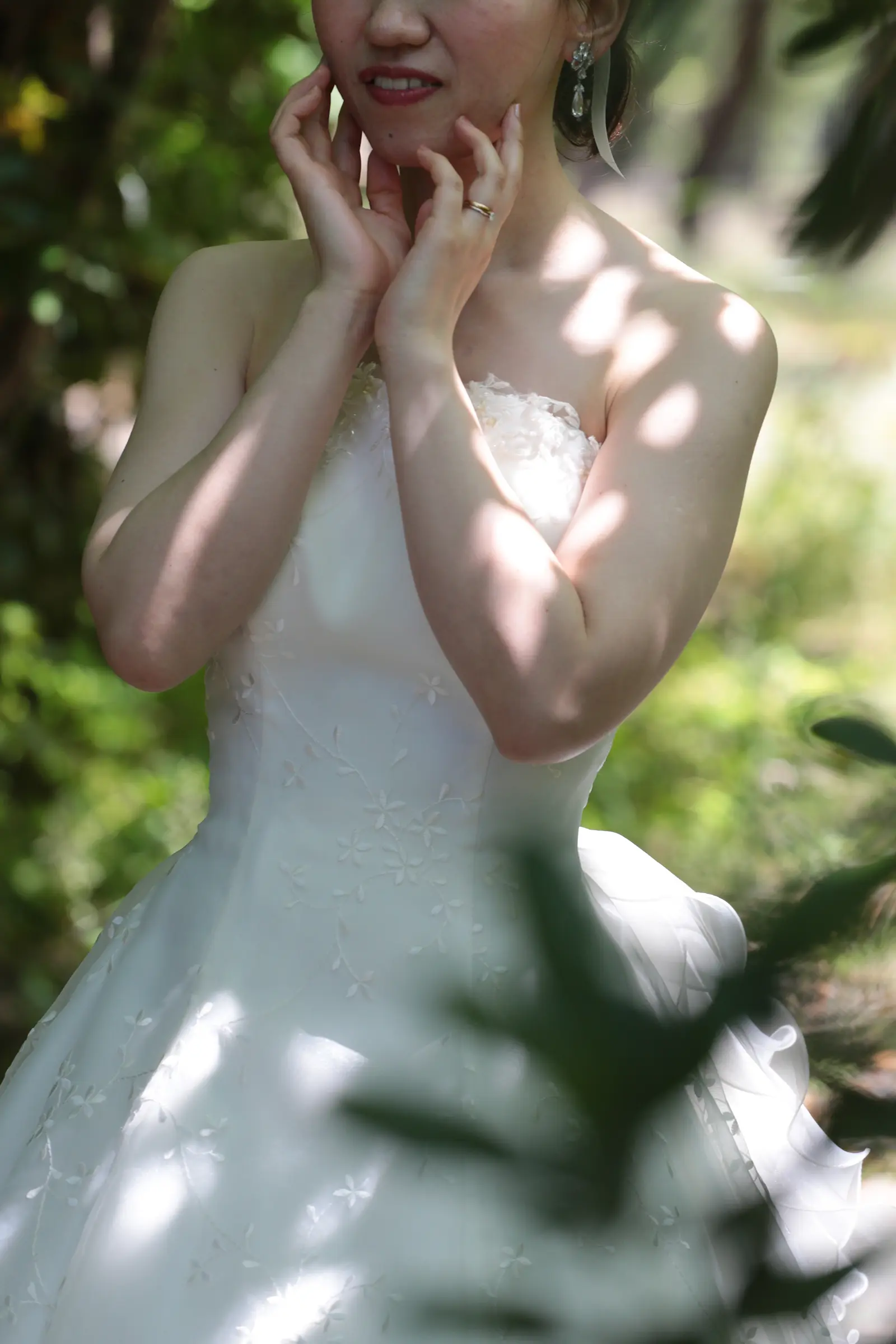 木漏れ日の中で頬に手を添える花嫁のクローズアップ写真