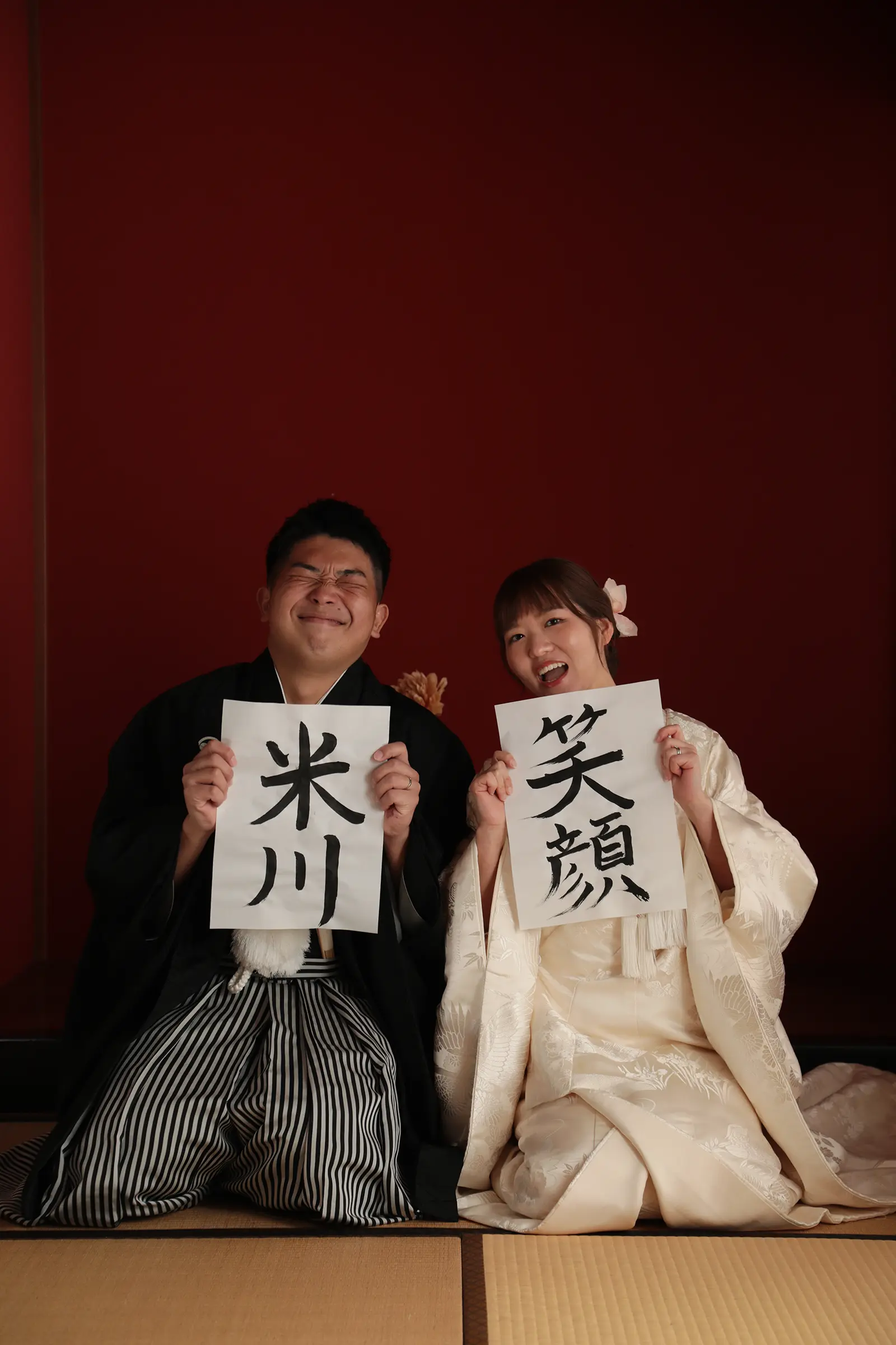 書いた文字を持って笑顔を見せる和装の新郎新婦