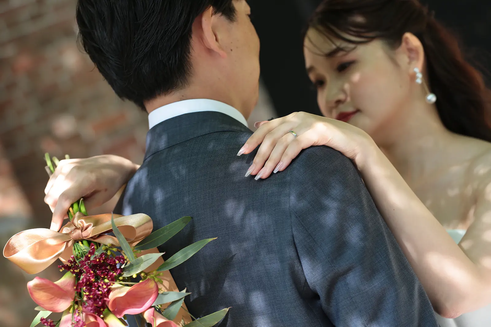 新郎に寄り添う花嫁の手元と指輪を写した写真