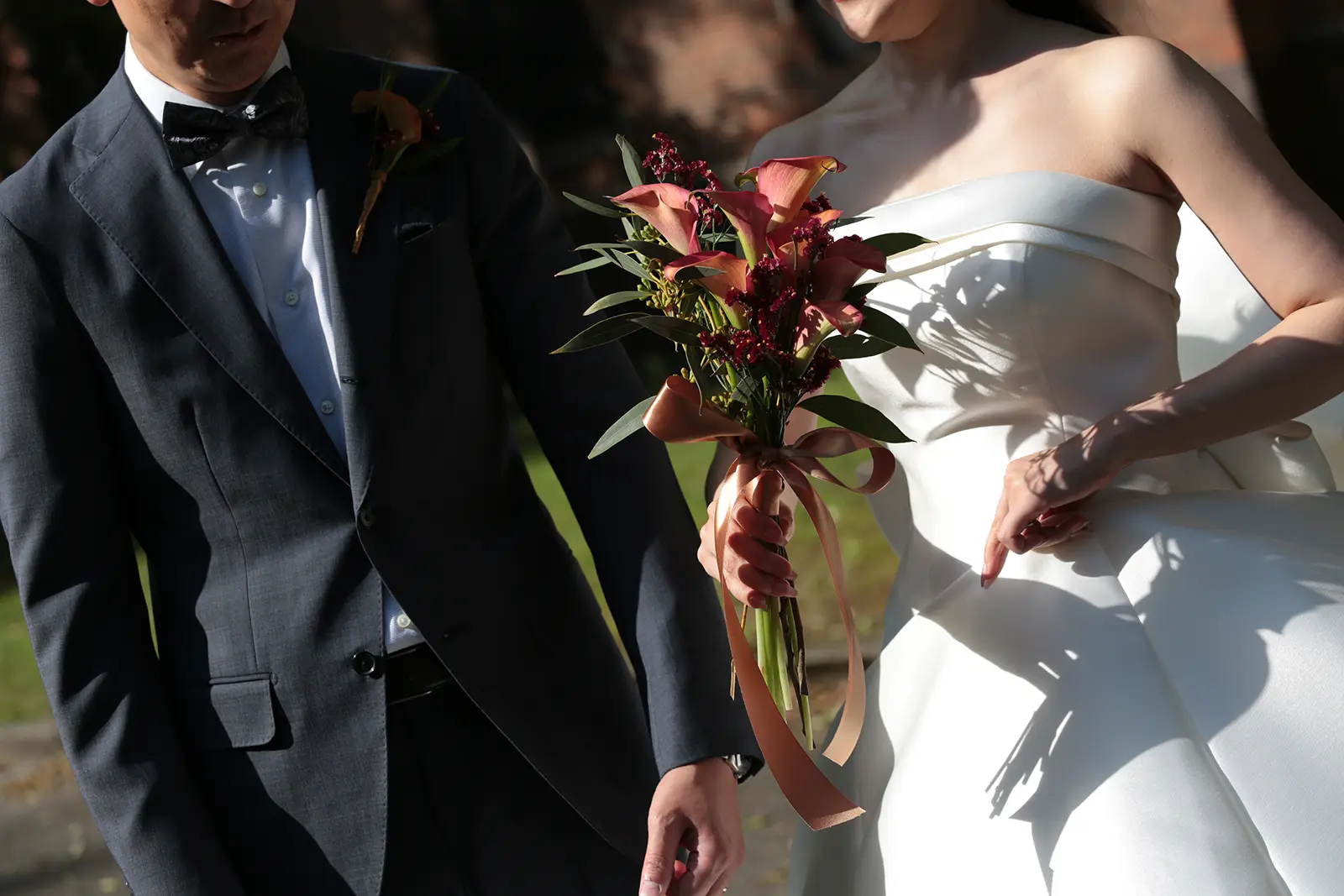 歩く新郎新婦の一部と花嫁のブーケを写した写真