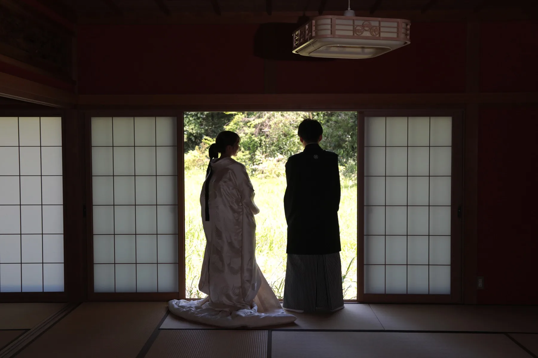 和室スタジオで庭を望む白無垢の花嫁と黒紋付の新郎の後ろ姿シルエット｜金沢のフォトウェディング