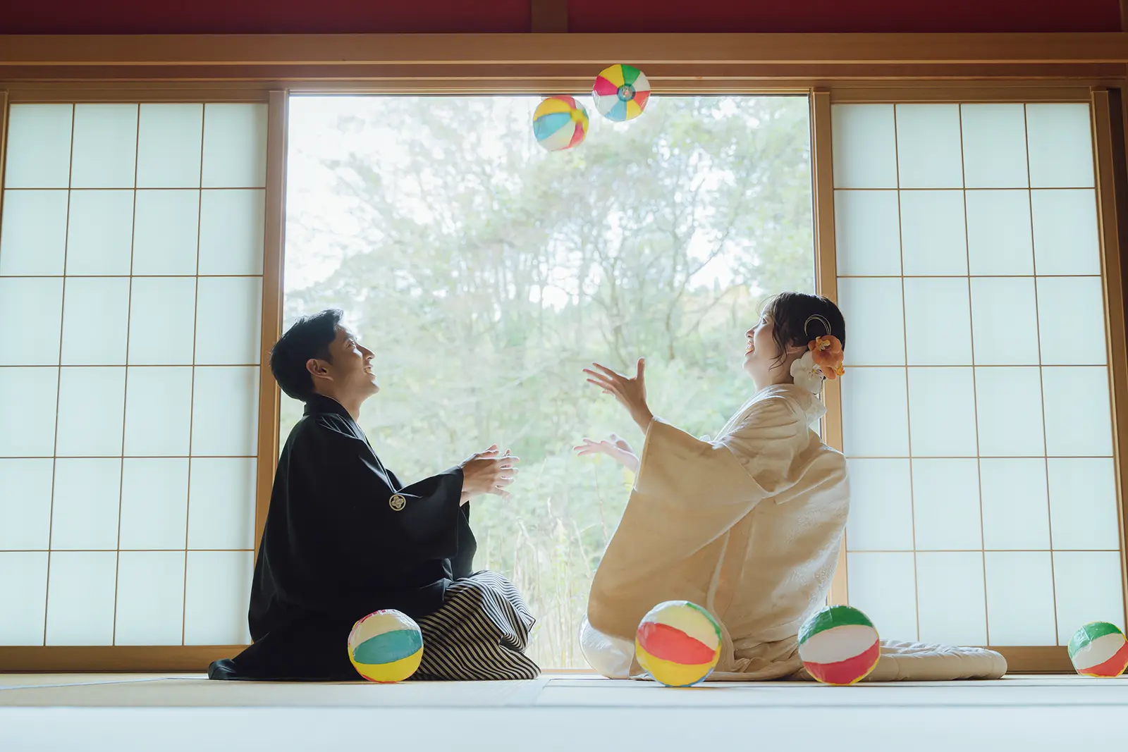 金沢のスタジオで手まりを投げながら笑い合う白無垢姿の新婦と紋付袴姿の新郎