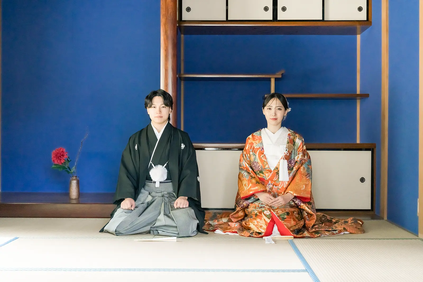 金沢のスタジオで青い壁を背景に正座する和装姿の新郎新婦