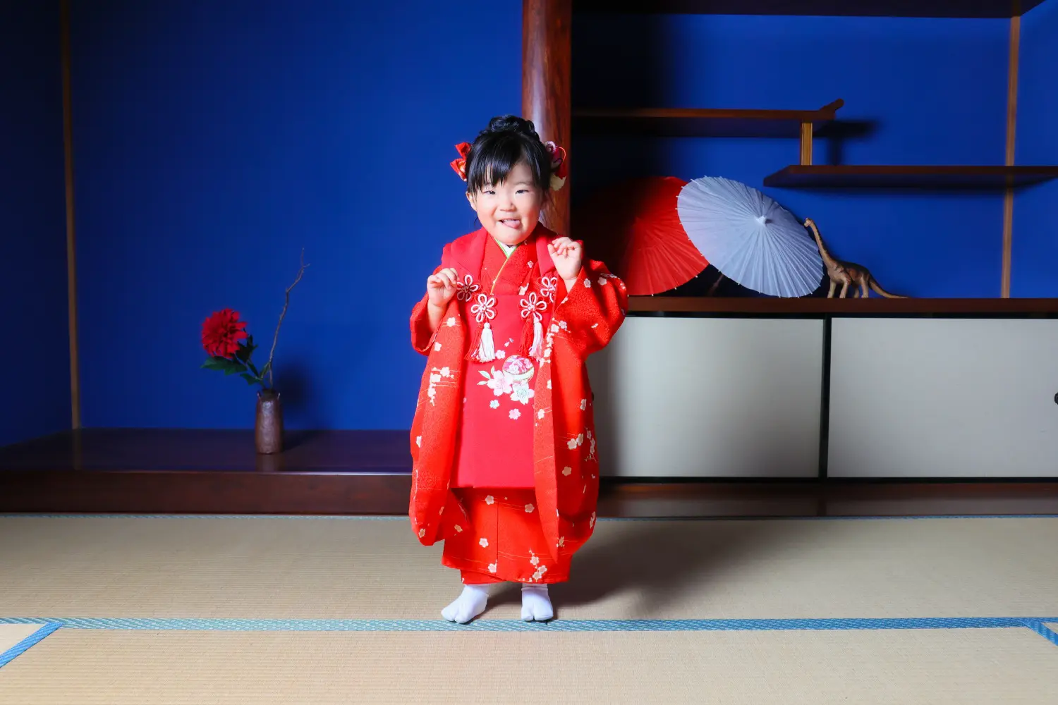 和室セットで両こぶしを上げてポーズする3歳の女の子、赤い被布姿の七五三スタジオ撮影（金沢店）