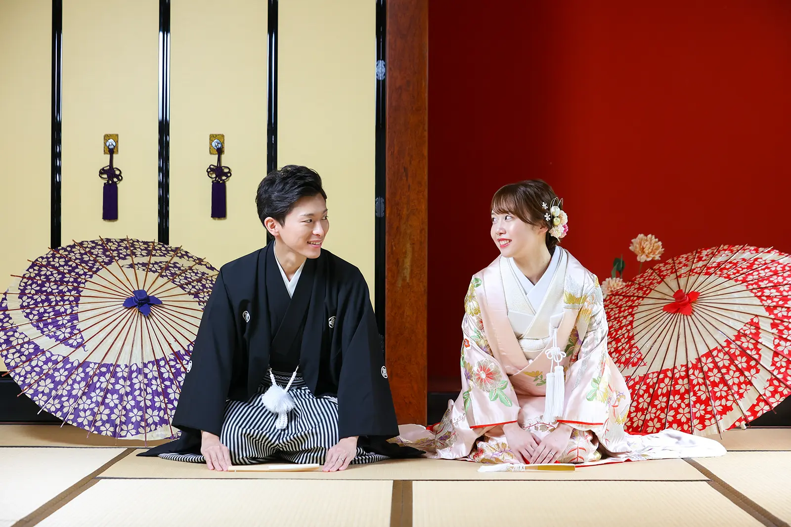金沢のスタジオで和傘を背景に座る和装姿の新郎新婦