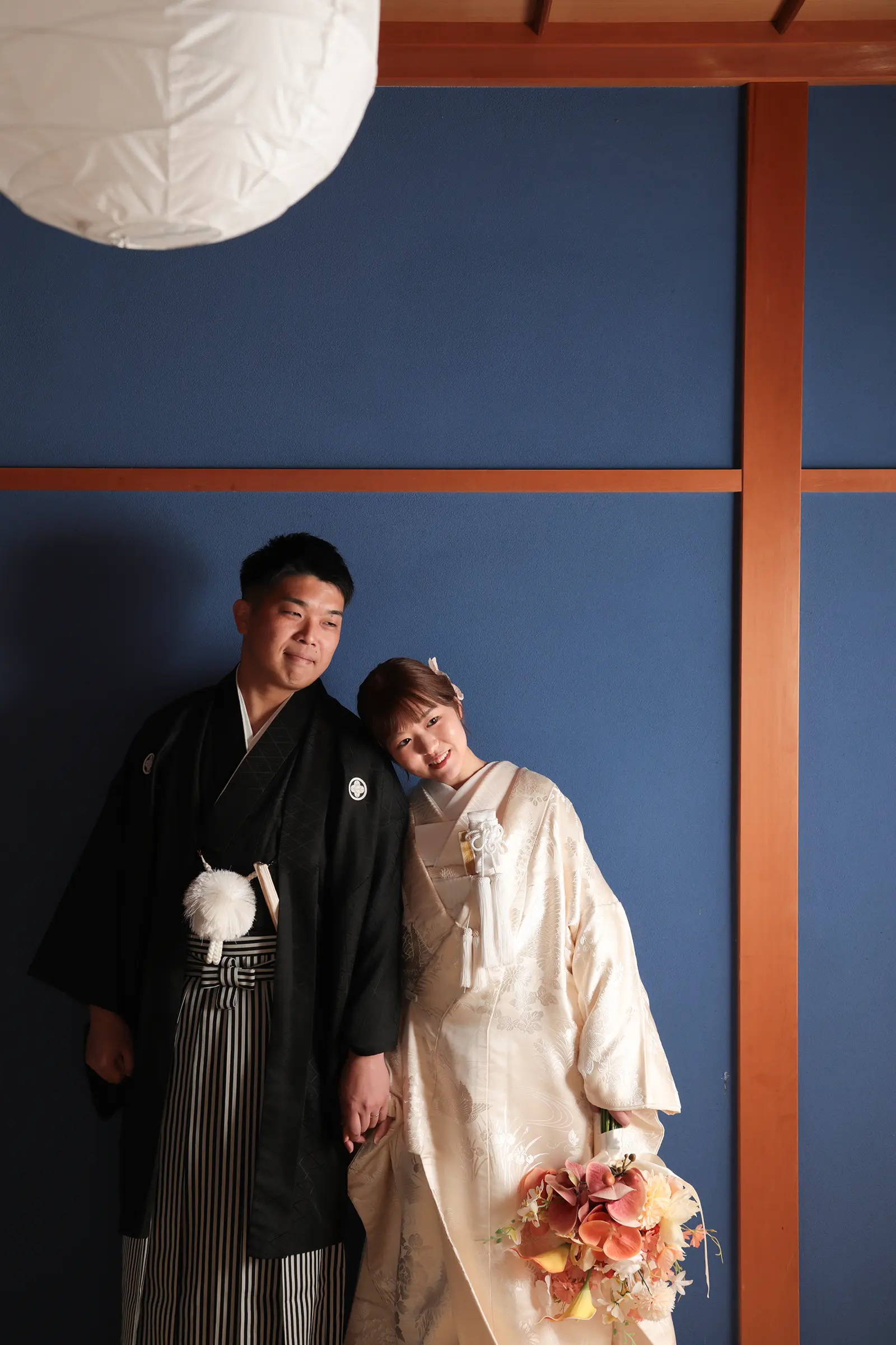 金沢のスタジオで青い壁を背景に寄り添う白無垢姿の新婦と紋付袴の新郎