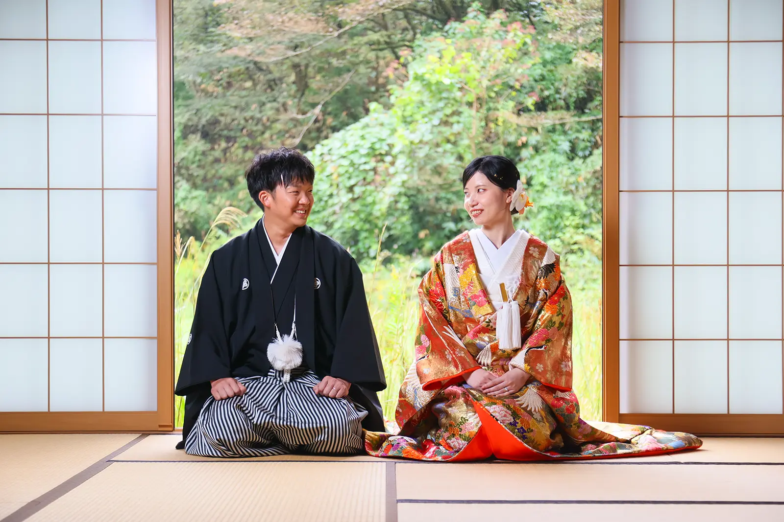 金沢のスタジオで窓辺に並んで座る和装姿の新郎新婦