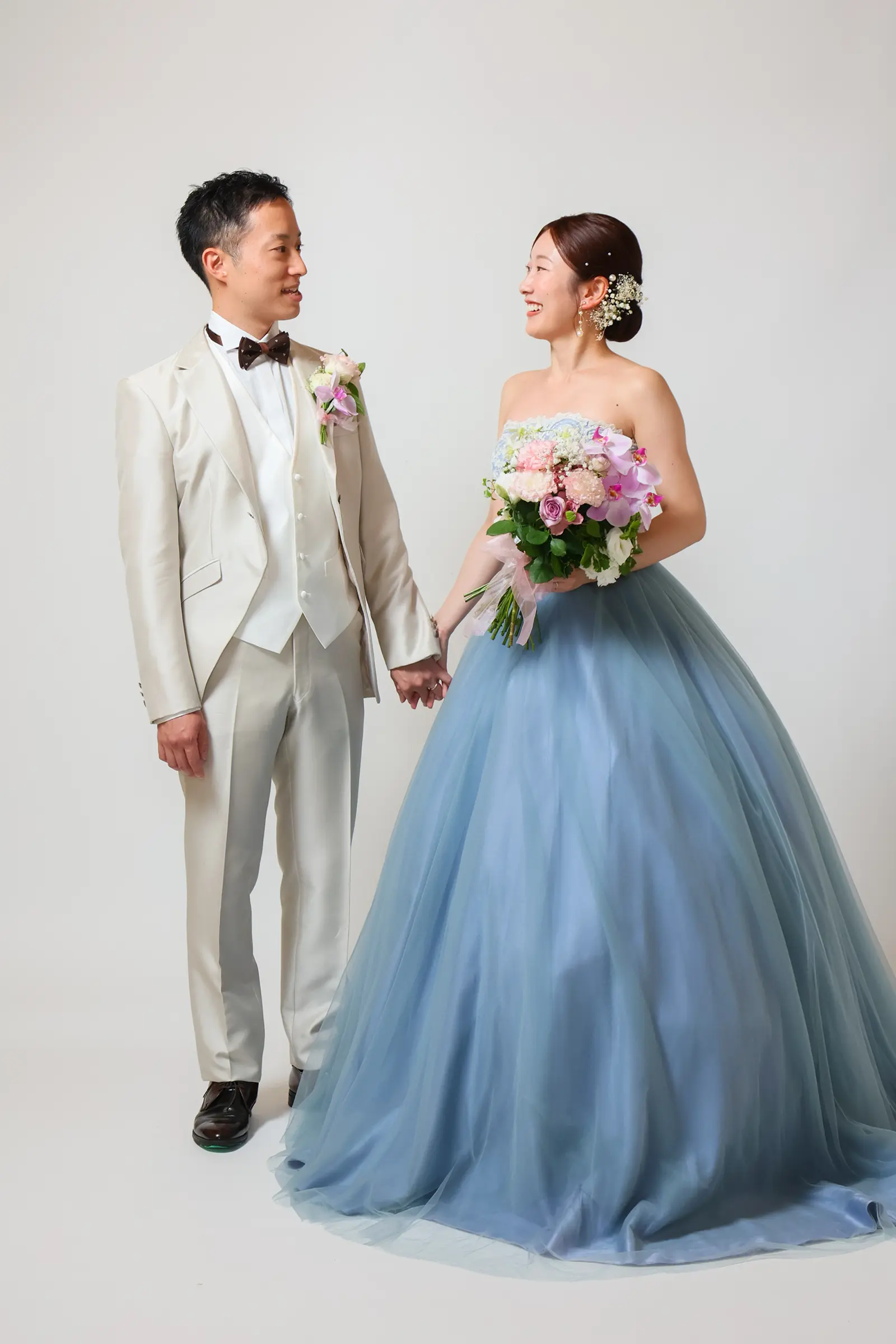 金沢のスタジオでブルードレスと白タキシード姿で立つ新郎新婦