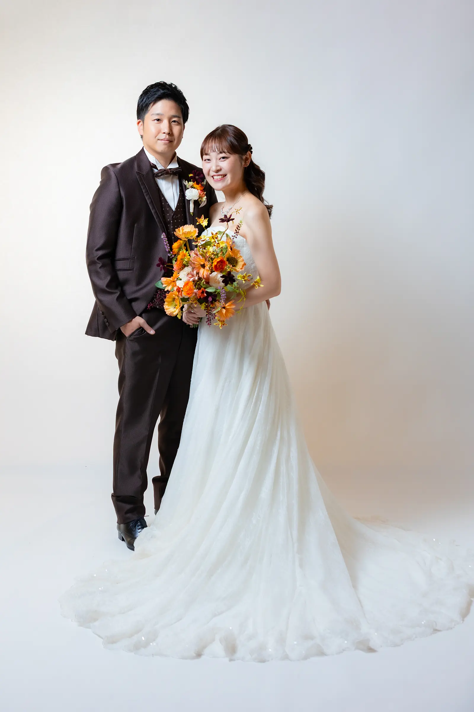 金沢のスタジオでブラウンタキシードと白ドレス姿で並ぶ新郎新婦
