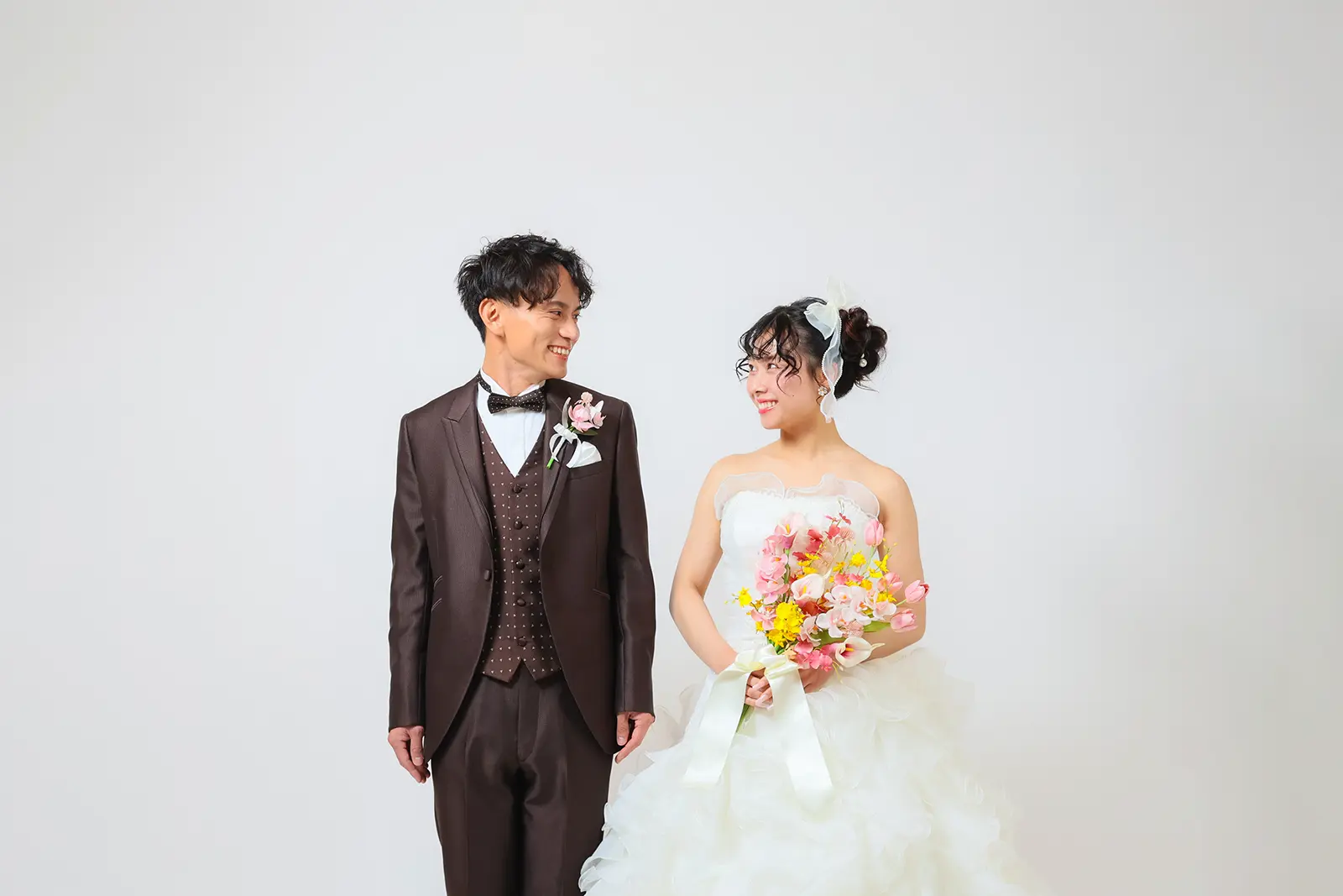 金沢のスタジオでブラウンタキシードと白ドレス姿で並ぶ新郎新婦