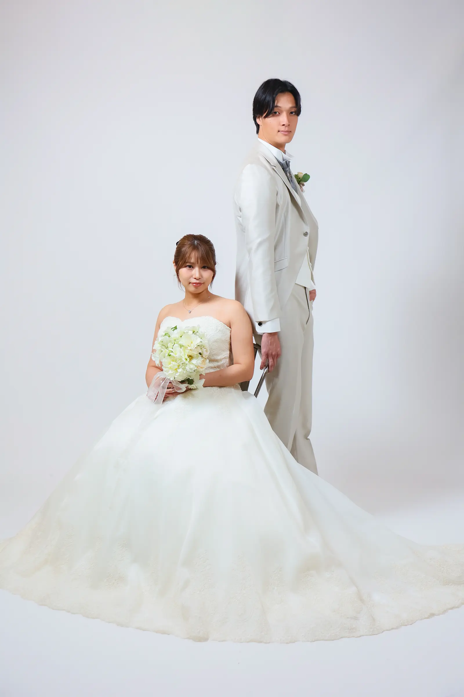 金沢のスタジオで白ドレス姿の新婦が座り白タキシード姿の新郎が立つ洋装写真