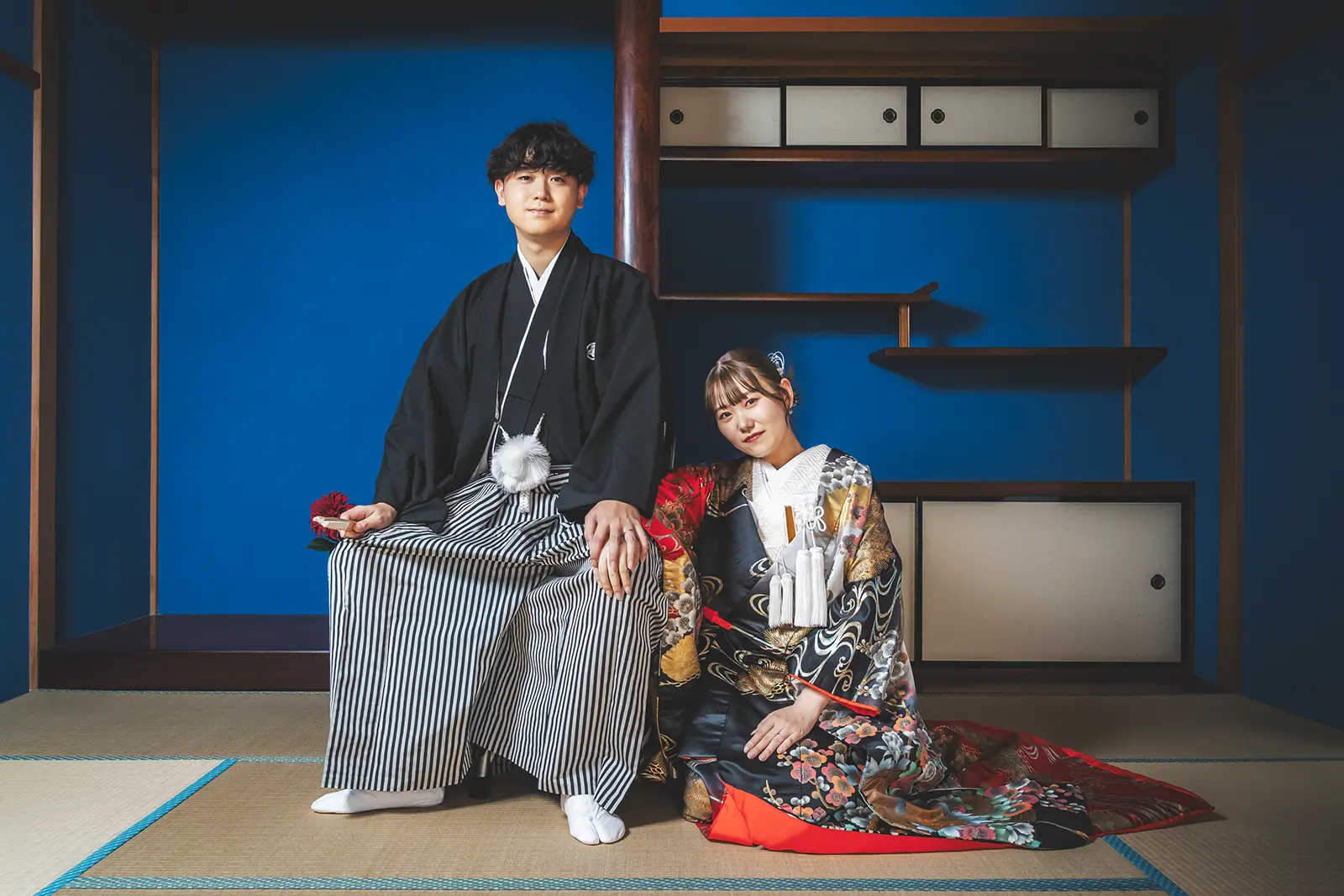 青い和室で正座する和装の新郎新婦