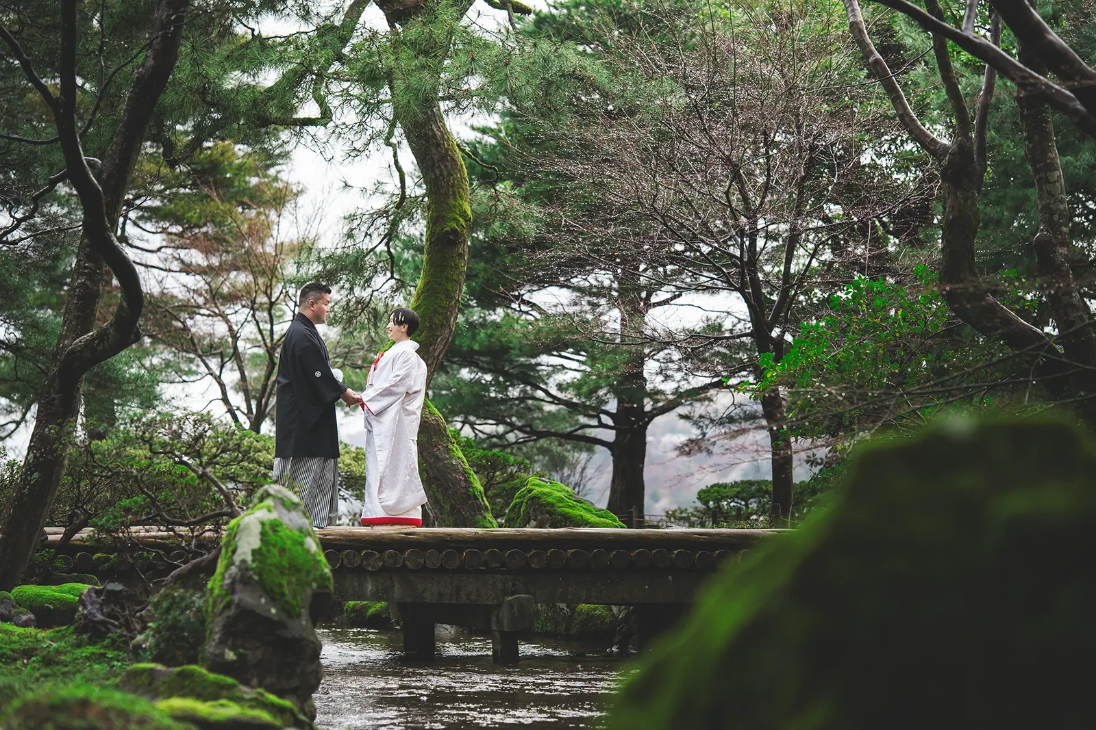 緑の庭園で向き合う和装の新郎新婦
