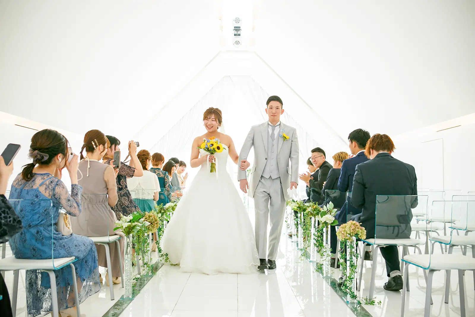 挙式＋会食のイメージとしてゲストに見守られながら入場する新郎新婦