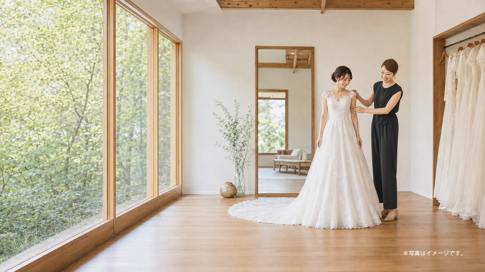 明るい試着室でスタッフに手を添えられながらウェディングドレスを合わせる花嫁(イメージ)