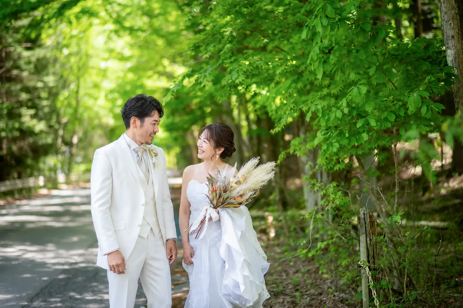軽井沢の新緑の森の小道で見つめ合う新郎新婦のフォトウェディング写真