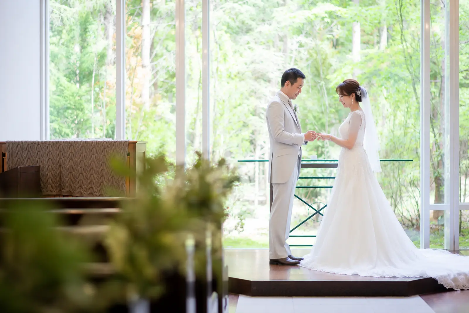 軽井沢のチャペルで新郎が新婦の指に指輪を添えるフォトウェディング写真
