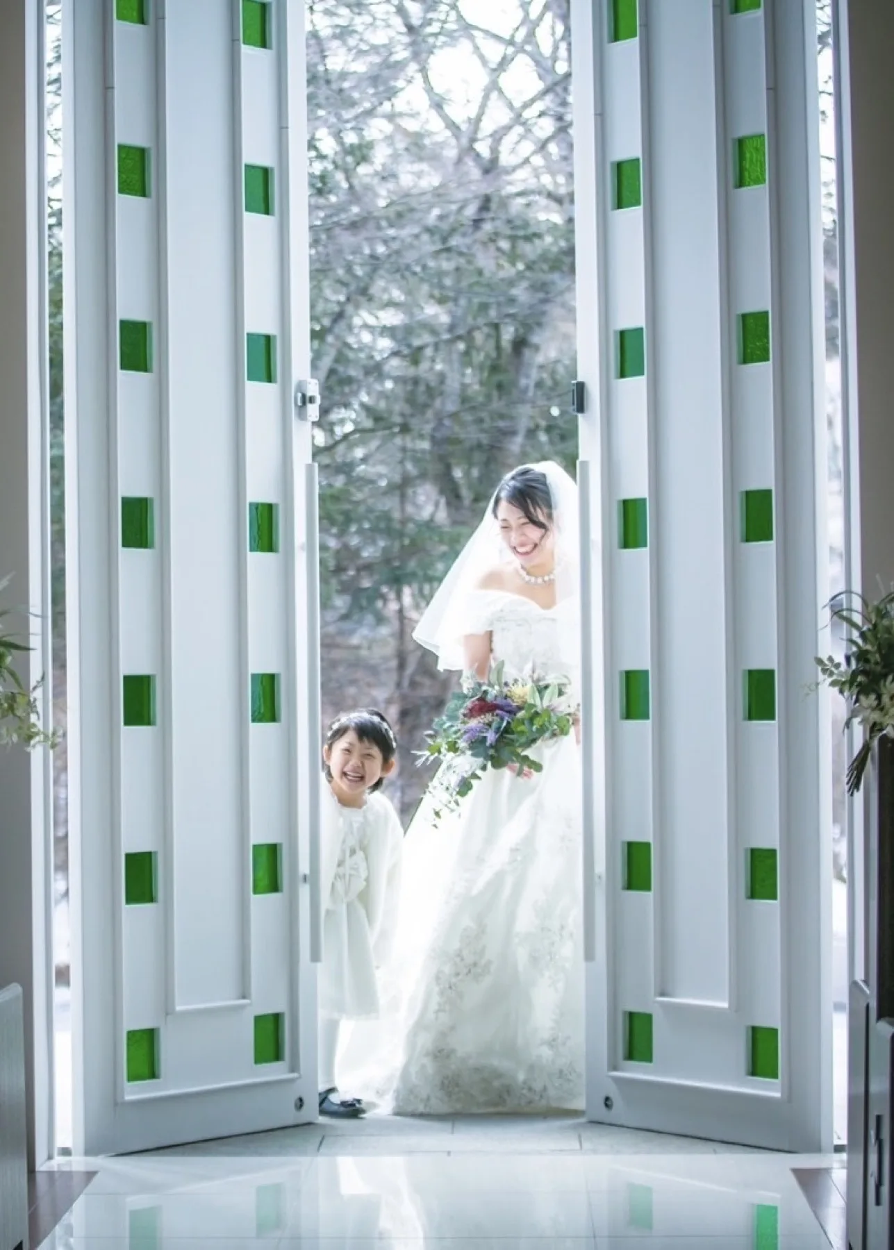軽井沢のチャペルでウェディングドレスを着てブーケを持つ新婦、大きな窓から森が見える