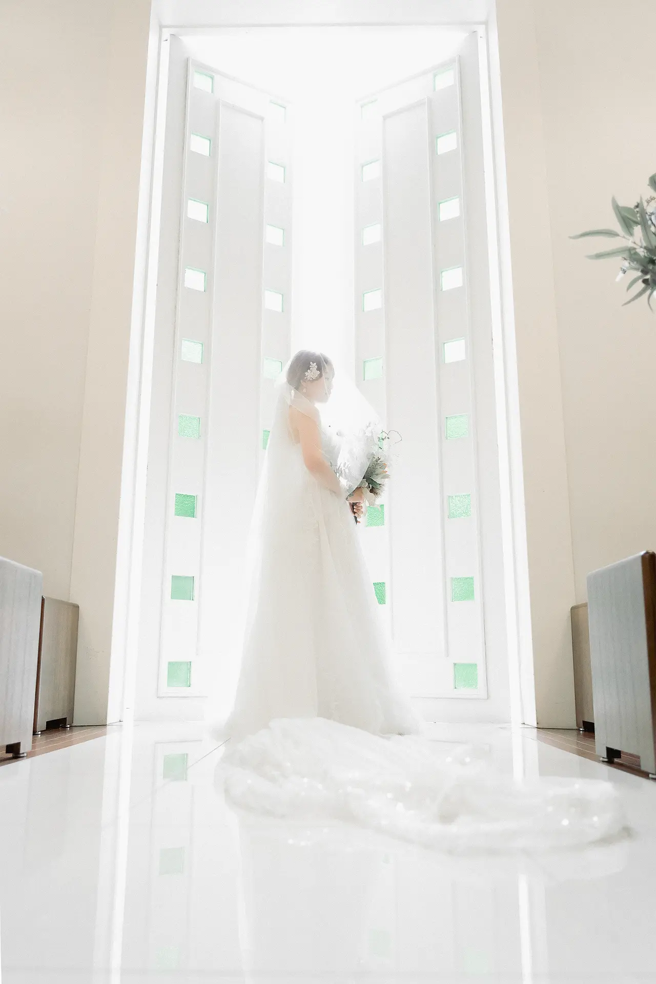 森のチャペル軽井沢礼拝堂のガラス越しに紅葉の森を背景にした新郎新婦の写真