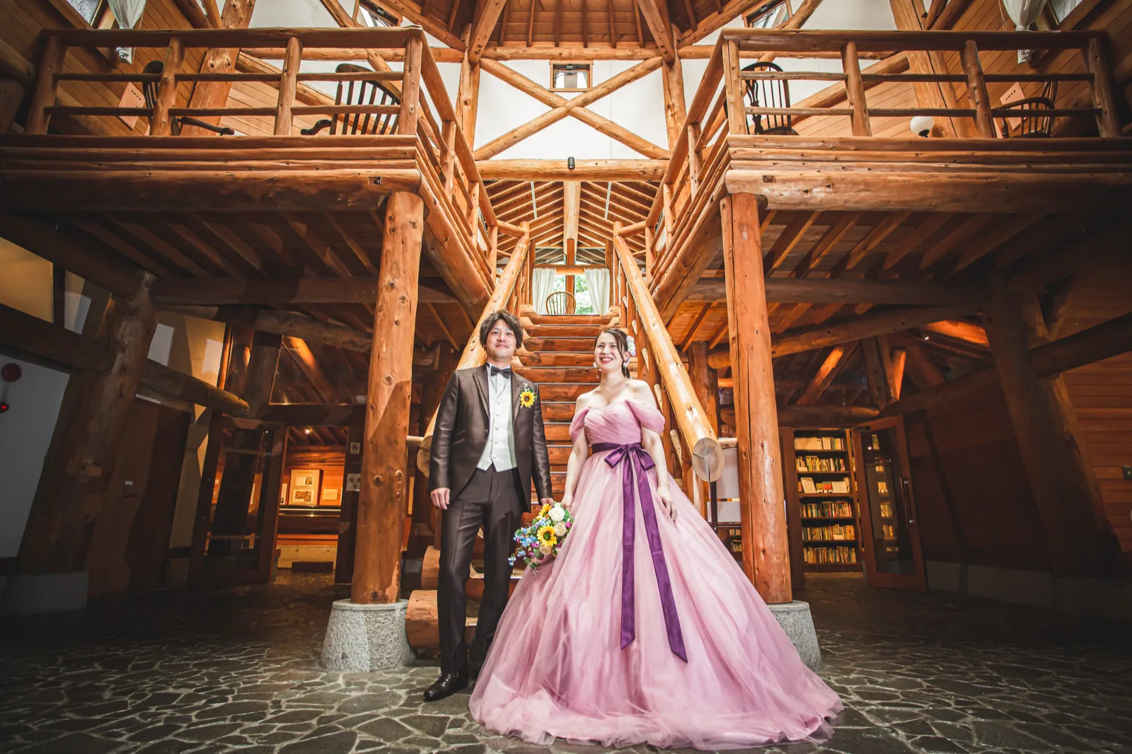 軽井沢・ムーゼの森の木組みのホールでピンクのカラードレスを着た新婦と新郎の前撮り