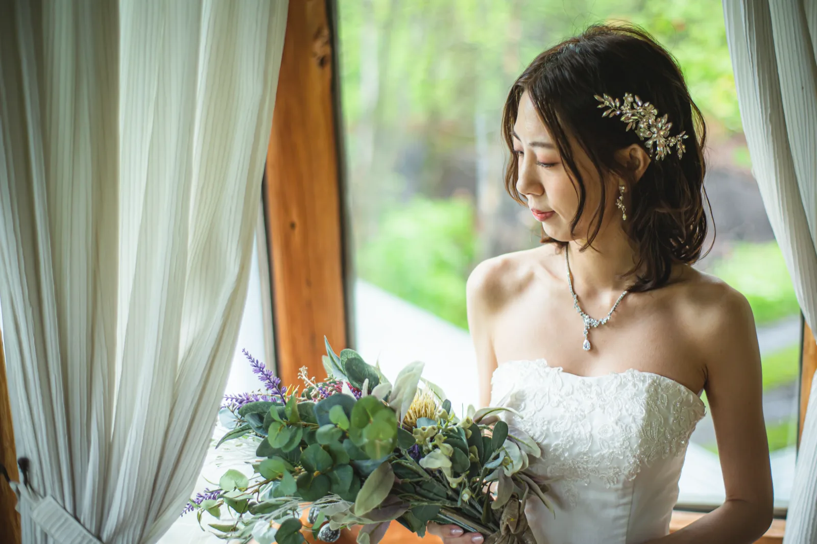 ムーゼの森の窓辺でブーケを持ち視線を落とす新婦の寄りのカット