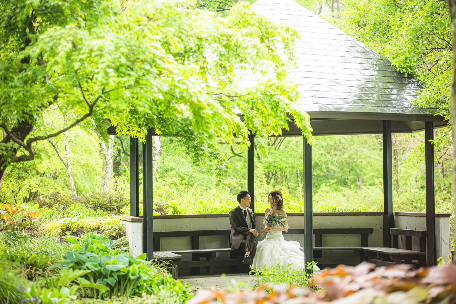 ムーゼの森のピクチャレスク・ガーデンの東屋に腰かける新郎新婦