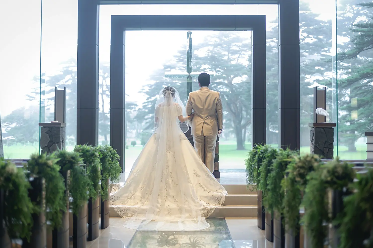 軽井沢プリンスホテルのガラス越しに紅葉の森を背景にした新郎新婦の写真