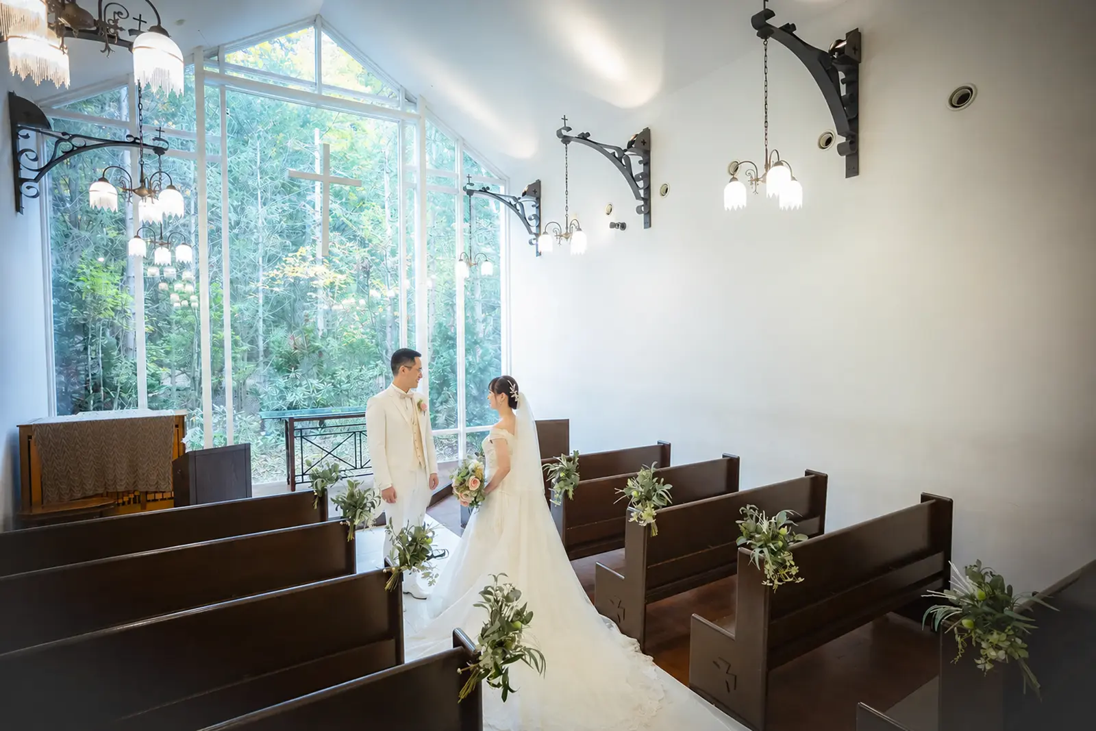 森が見える軽井沢のチャペル祭壇前で向かい合う新郎新婦のフォトウェディング写真
