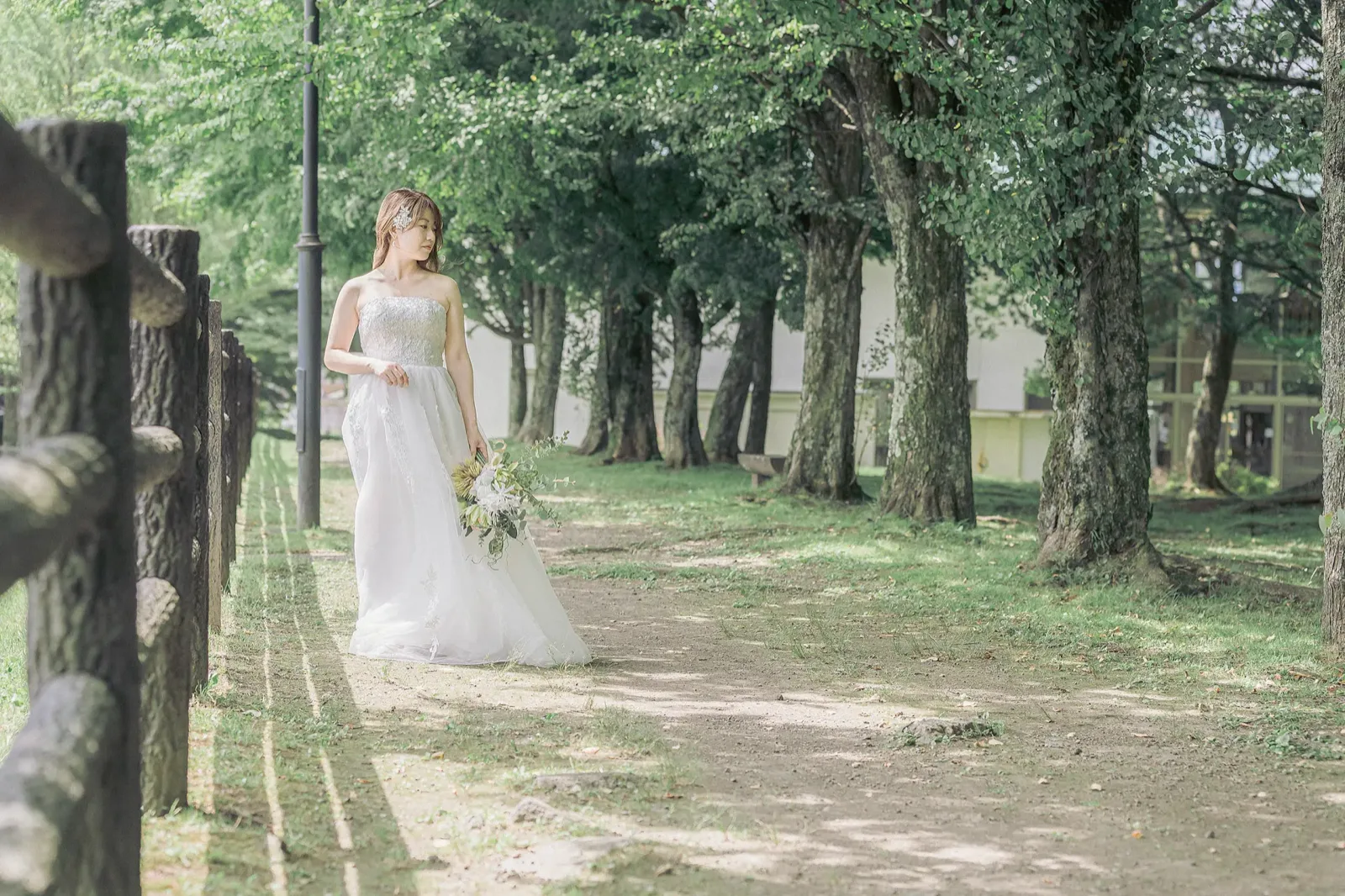 矢ヶ崎公園の木立の道をドレスで歩く新婦